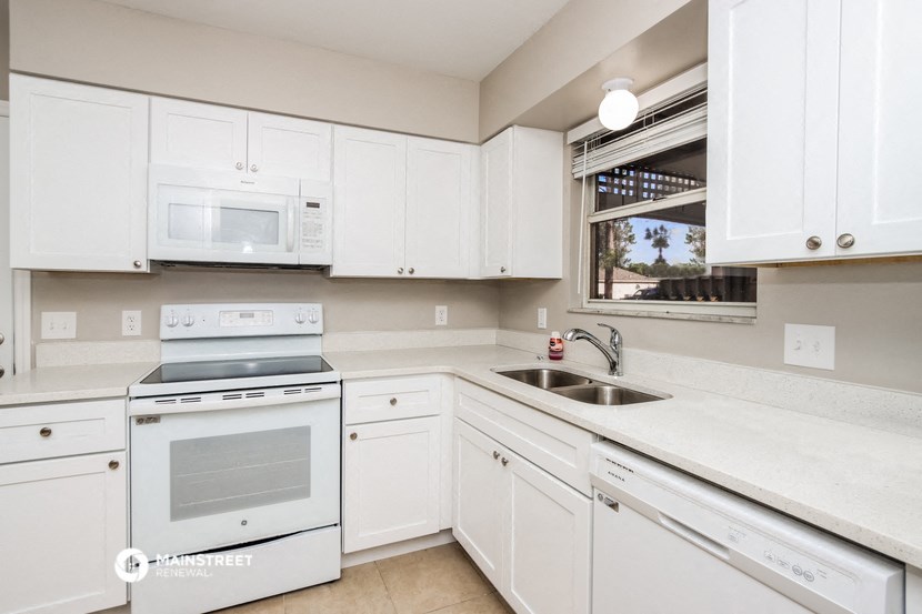 a kitchen with white cabinets and white appliances and a sink