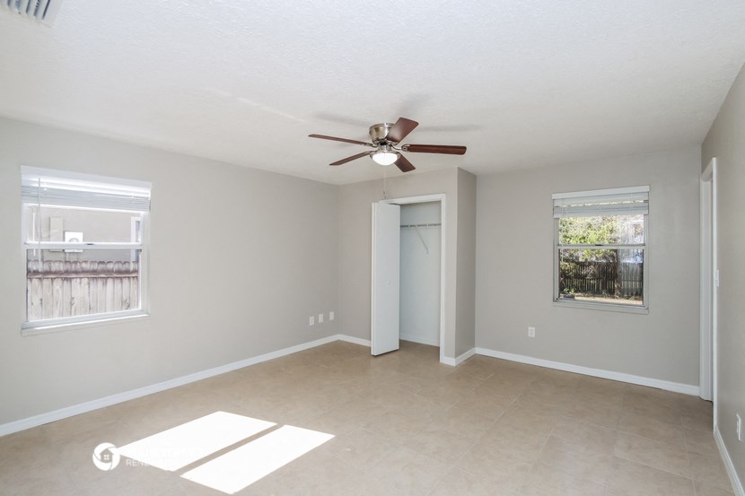 an empty living room with a ceiling fan