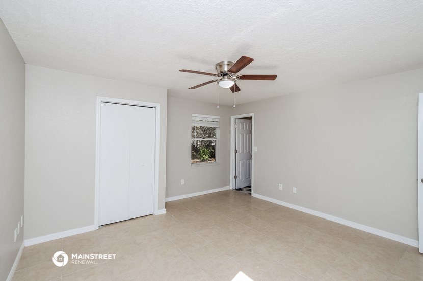 the spacious living room with ceiling fan and tile flooring