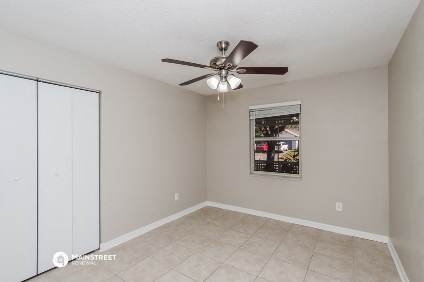 an empty living room with a ceiling fan and a closet