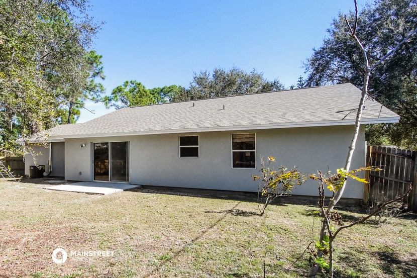 a small white house with a yard and trees