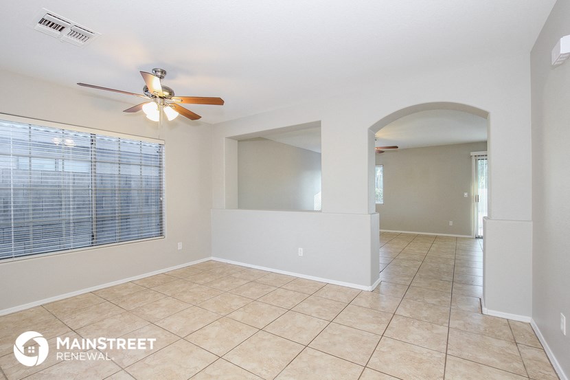 an empty living room with a ceiling fan and a large window
