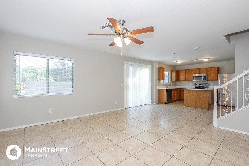 an empty kitchen with a ceiling fan and a staircase