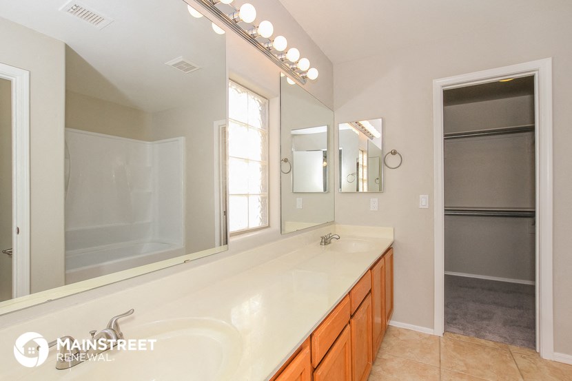 the master bathroom has a large vanity with a large mirror and a shower