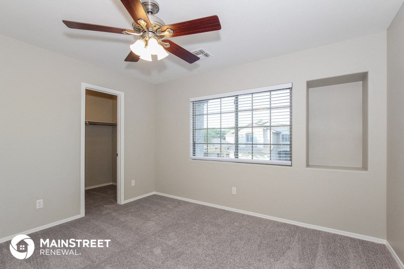 the spacious living room with ceiling fan and window