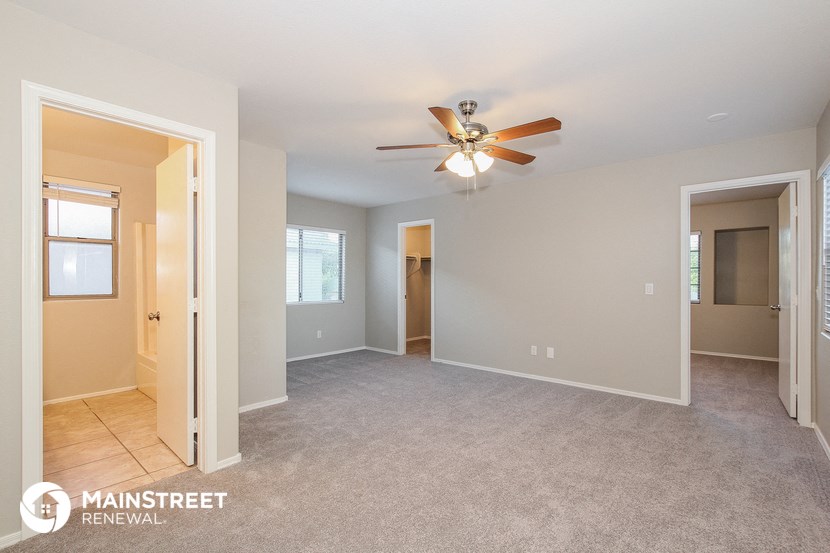 the living room of an empty house with a ceiling fan