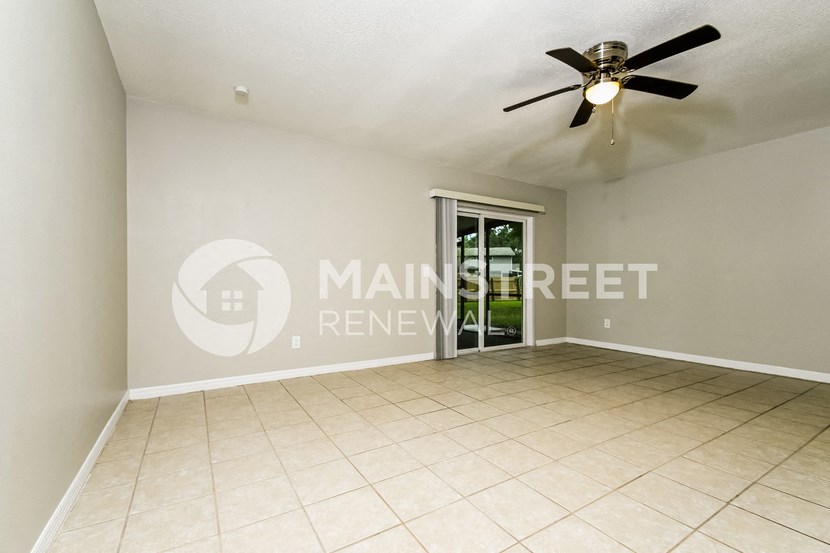 a empty living room with a ceiling fan and a door to a patio