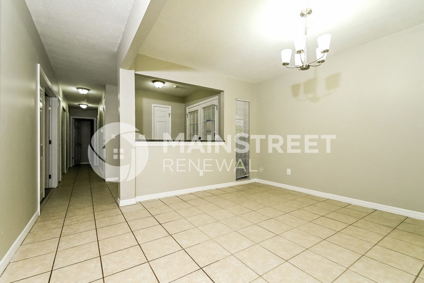 a large living room with tile flooring and a hallway with a door to a