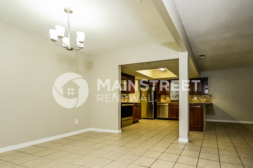 a lower level living room with a kitchen and a chandelier