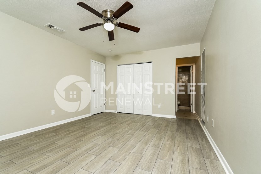 a large empty living room with a ceiling fan