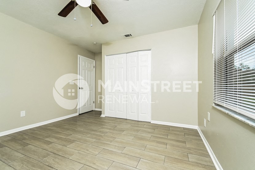 a large empty living room with a ceiling fan and a door