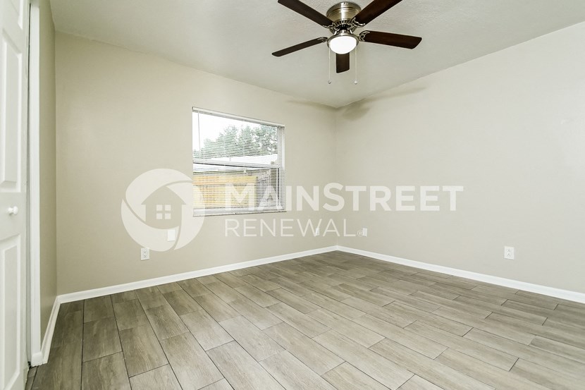 a living room with a large window and a ceiling fan