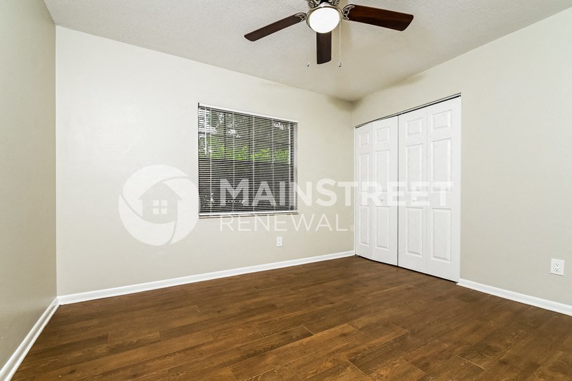 a bedroom with a hard wood floor and a ceiling fan