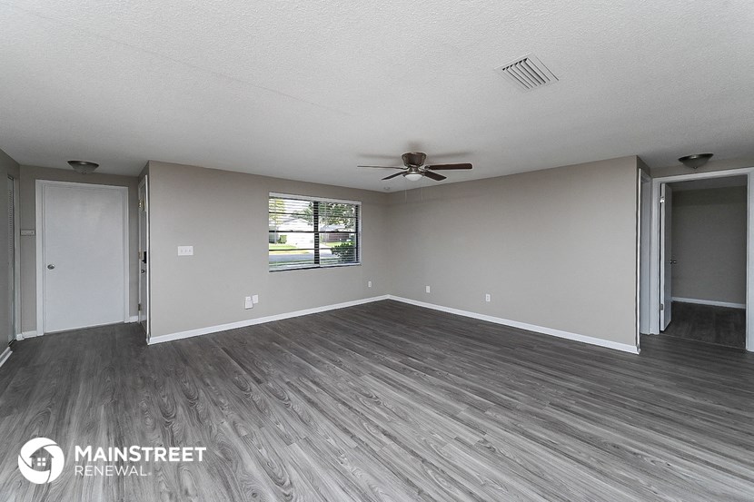 the living room of an empty house with wood flooring and a ceiling fan