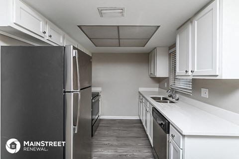 a kitchen with white cabinets and stainless steel appliances and a refrigerator