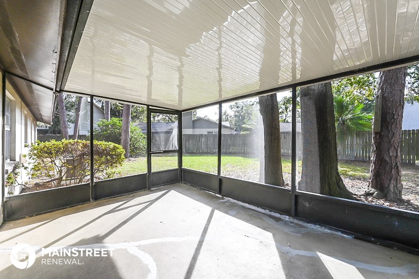 a screened in porch with a view of a yard and trees