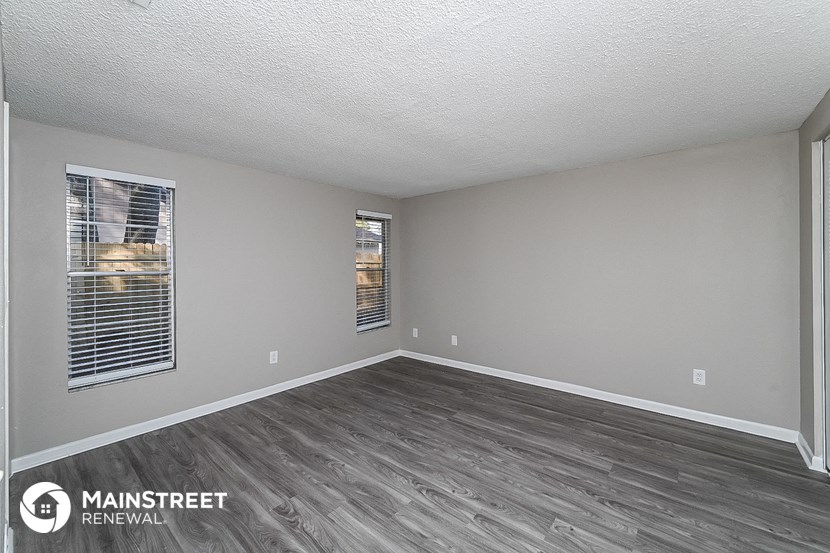 the living room of an apartment with wood floors and grey walls