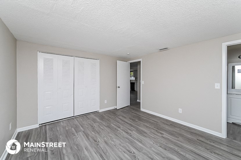 the living room of an apartment with wood flooring and white doors