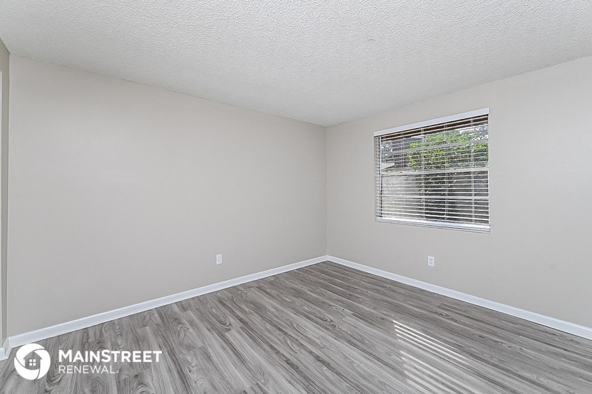 the spacious living room with wood flooring and a window