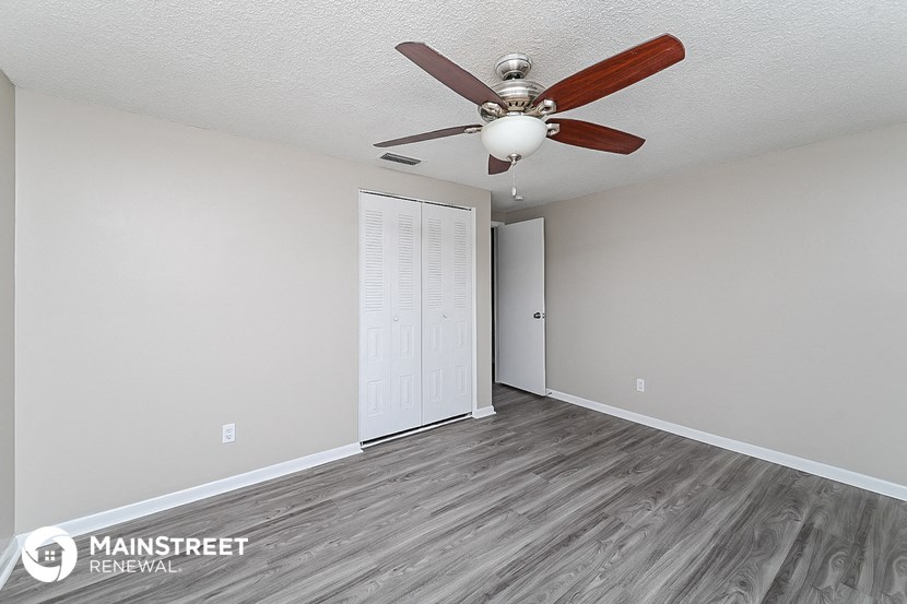the spacious living room with a ceiling fan and wood flooring