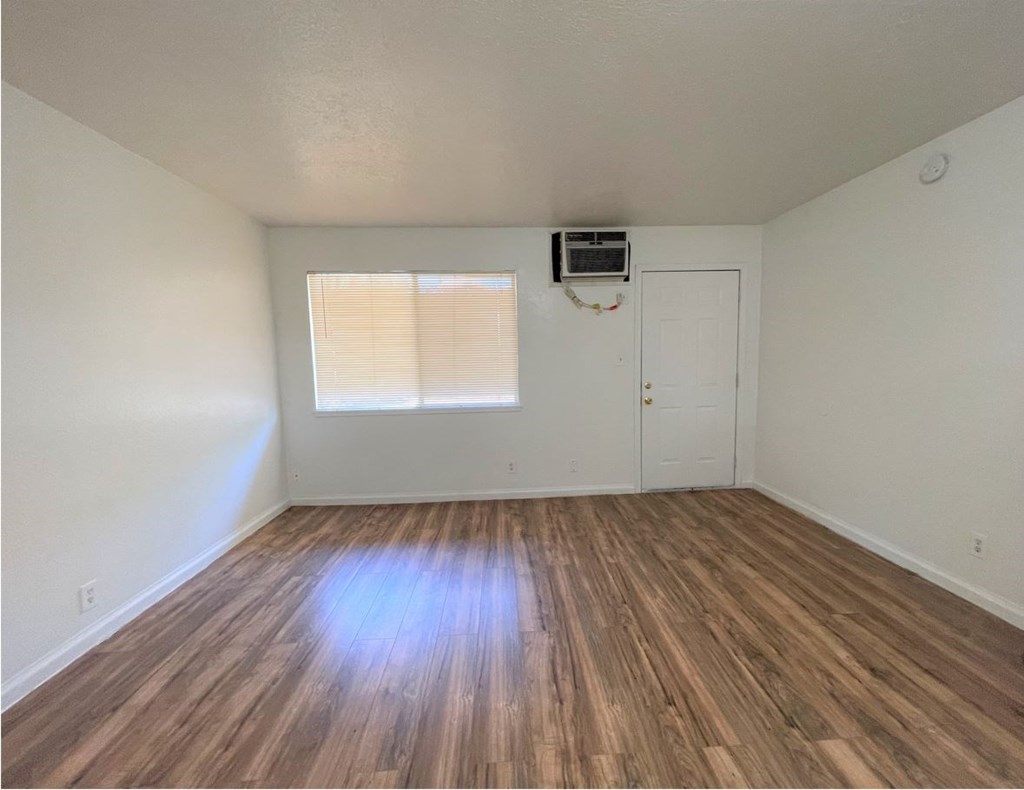 the living room of an empty house with wooden floors and a window