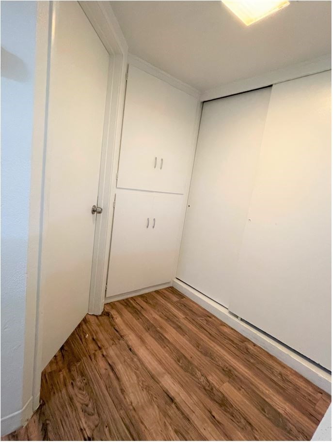 a small room with white cabinets and a wood floor
