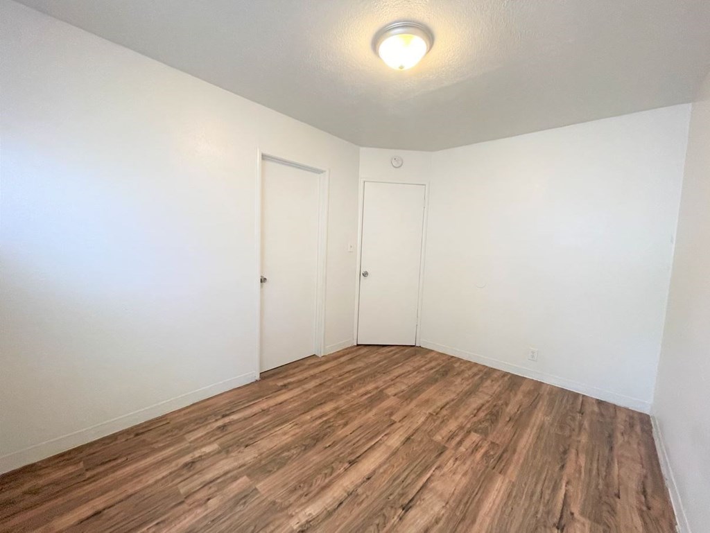 an empty room with white walls and wood flooring
