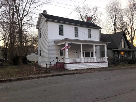 A white house with a red and blue American flag on the front porch.