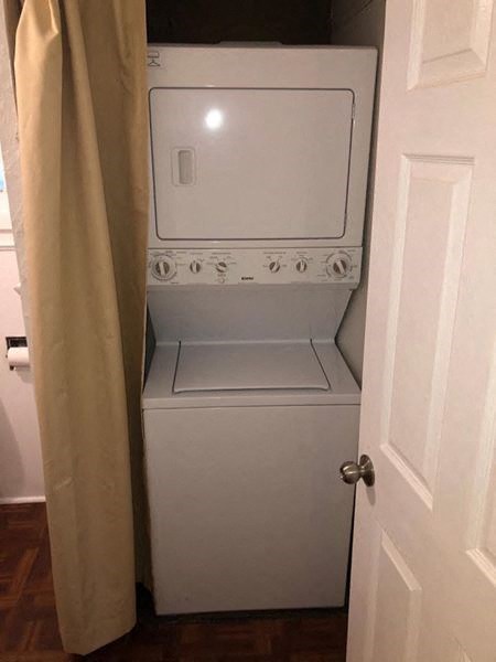 A white washing machine sits in a small laundry room.