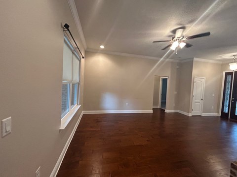 A room with a ceiling fan and wooden flooring.
