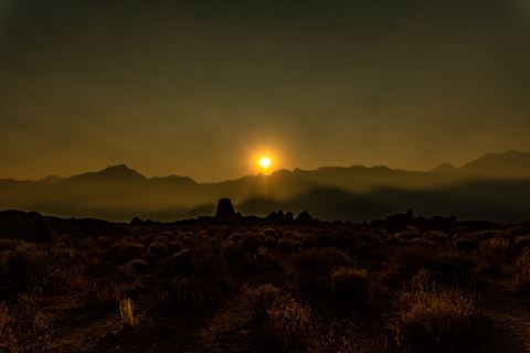 the sun setting over the mountains in the desert