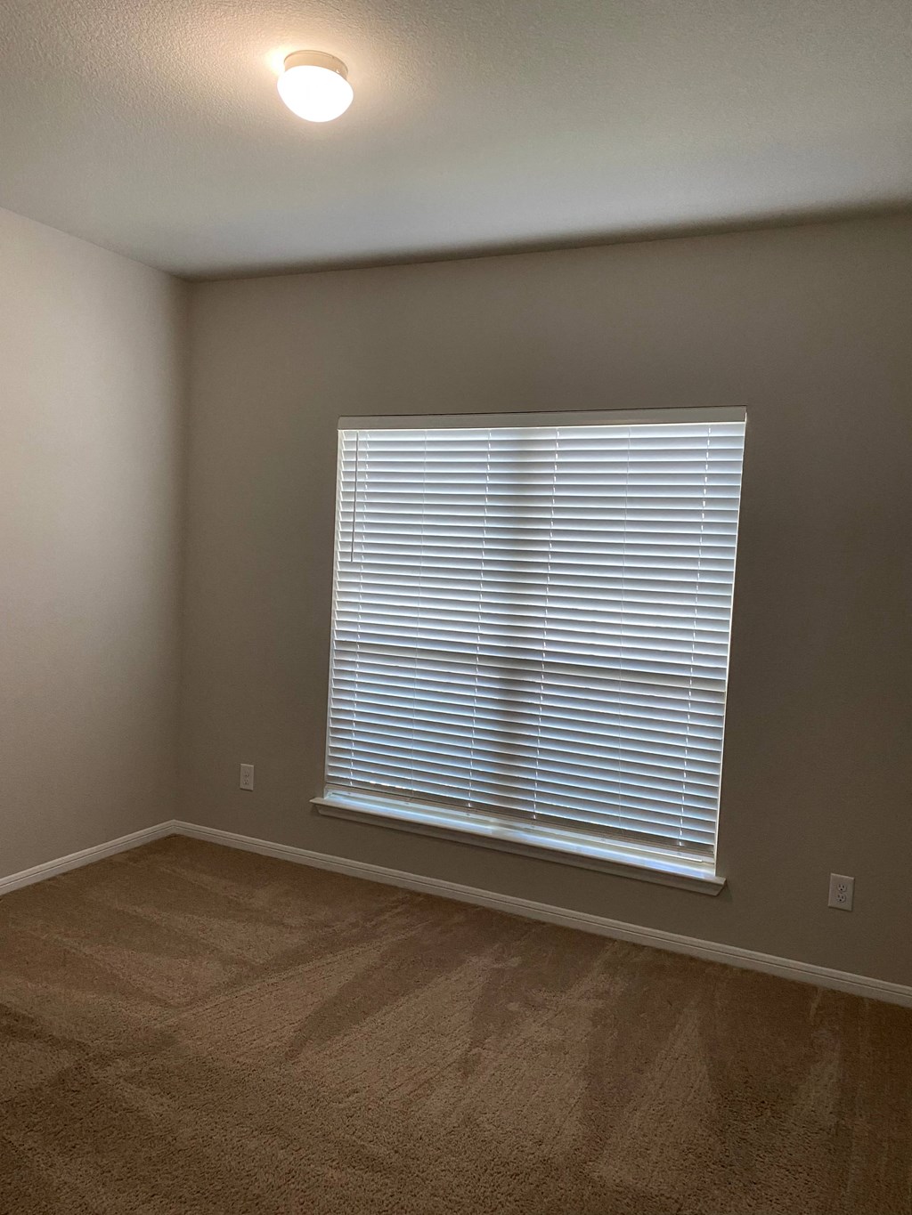 a living room with a large window and a carpeted floor