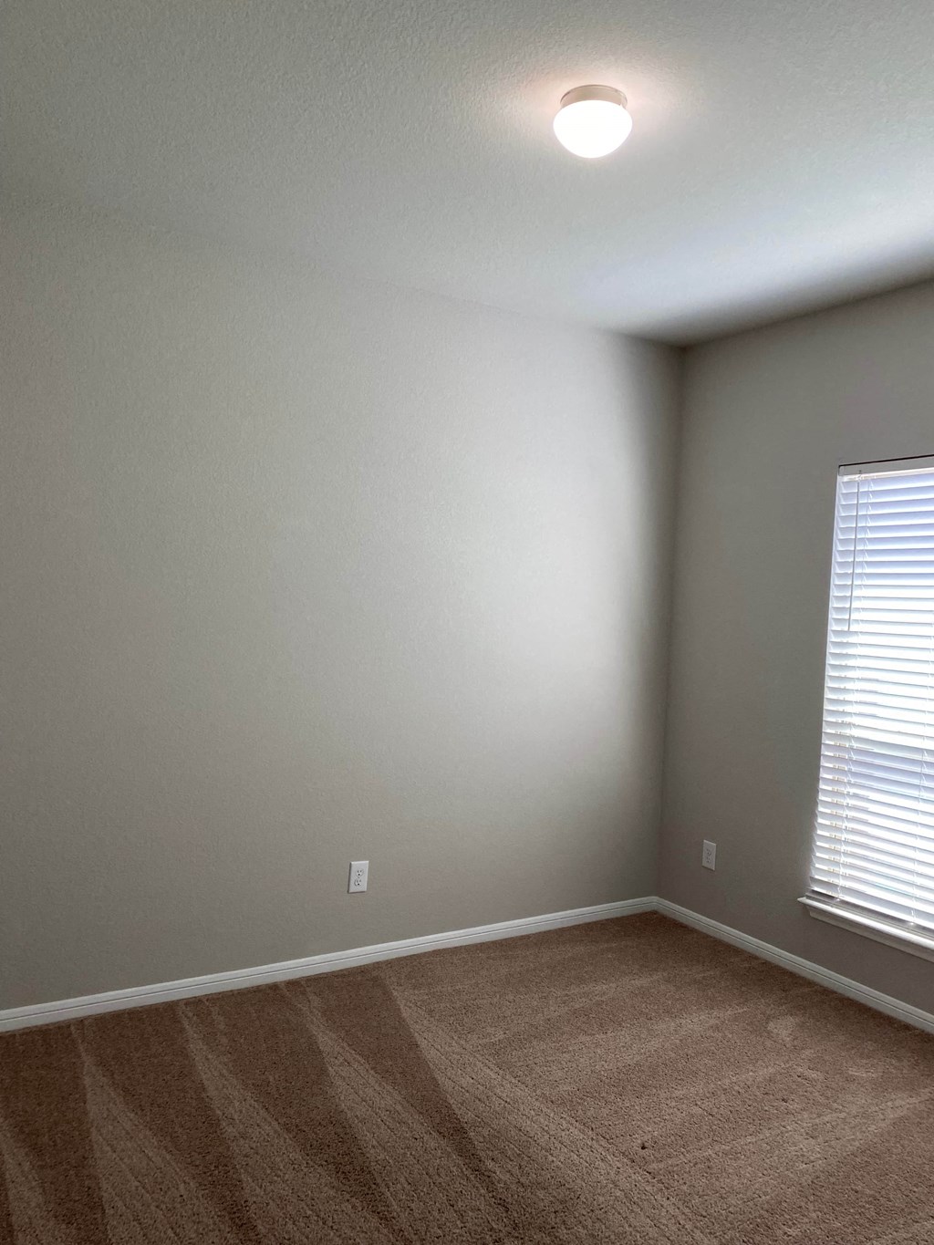 an empty room with a window and a carpet