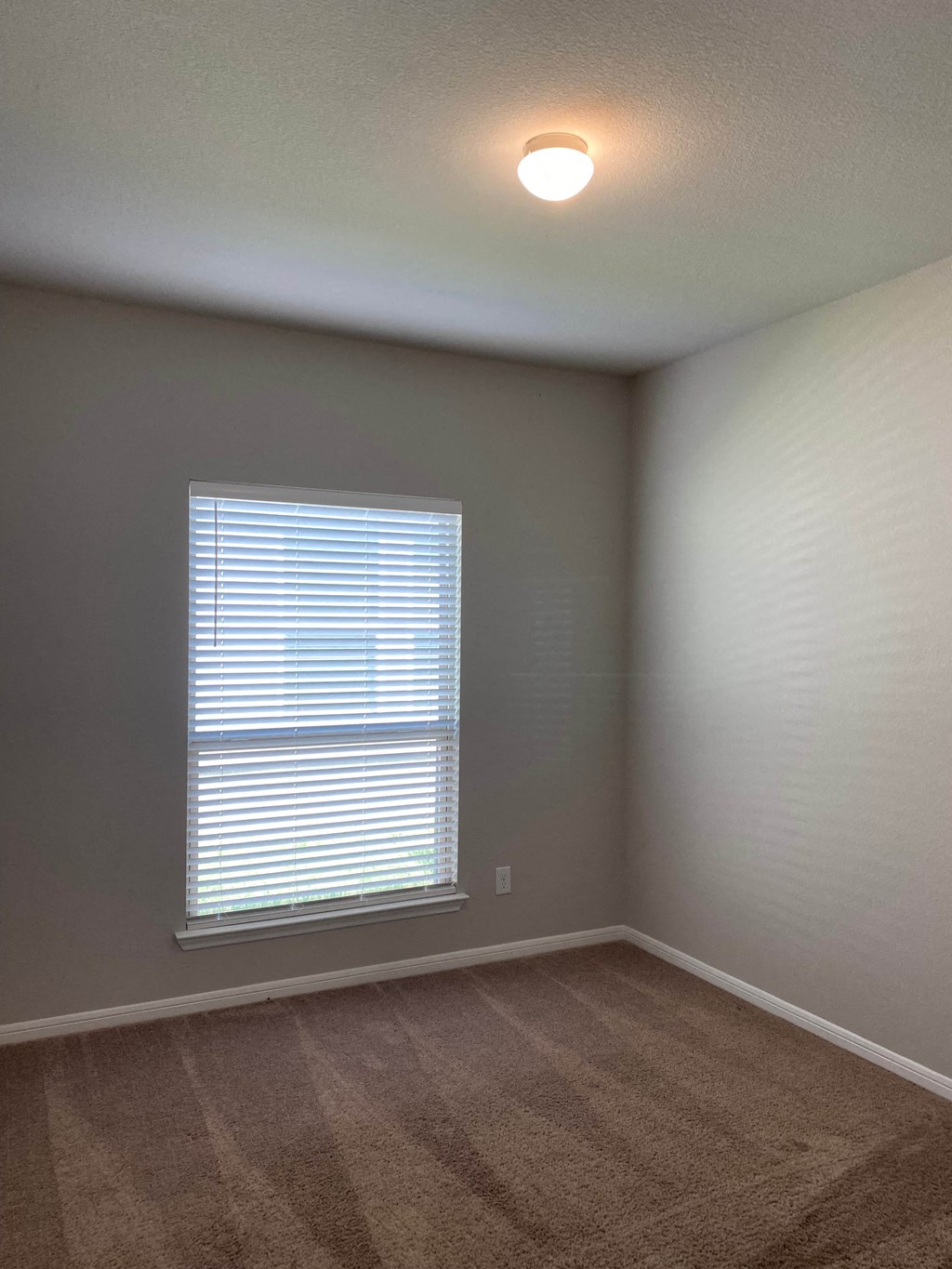 an empty living room with a window and carpet
