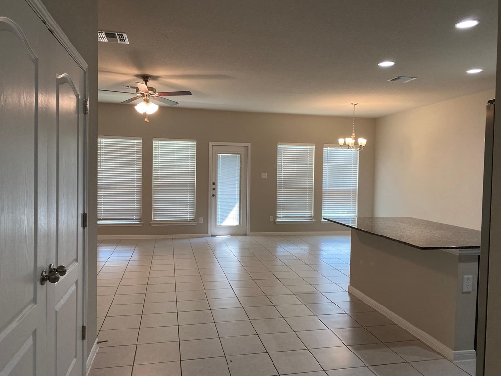 an empty living room with a ceiling fan and windows