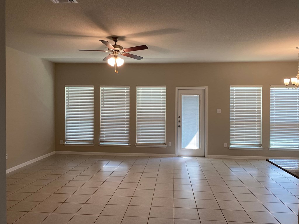 an empty living room with a ceiling fan and windows