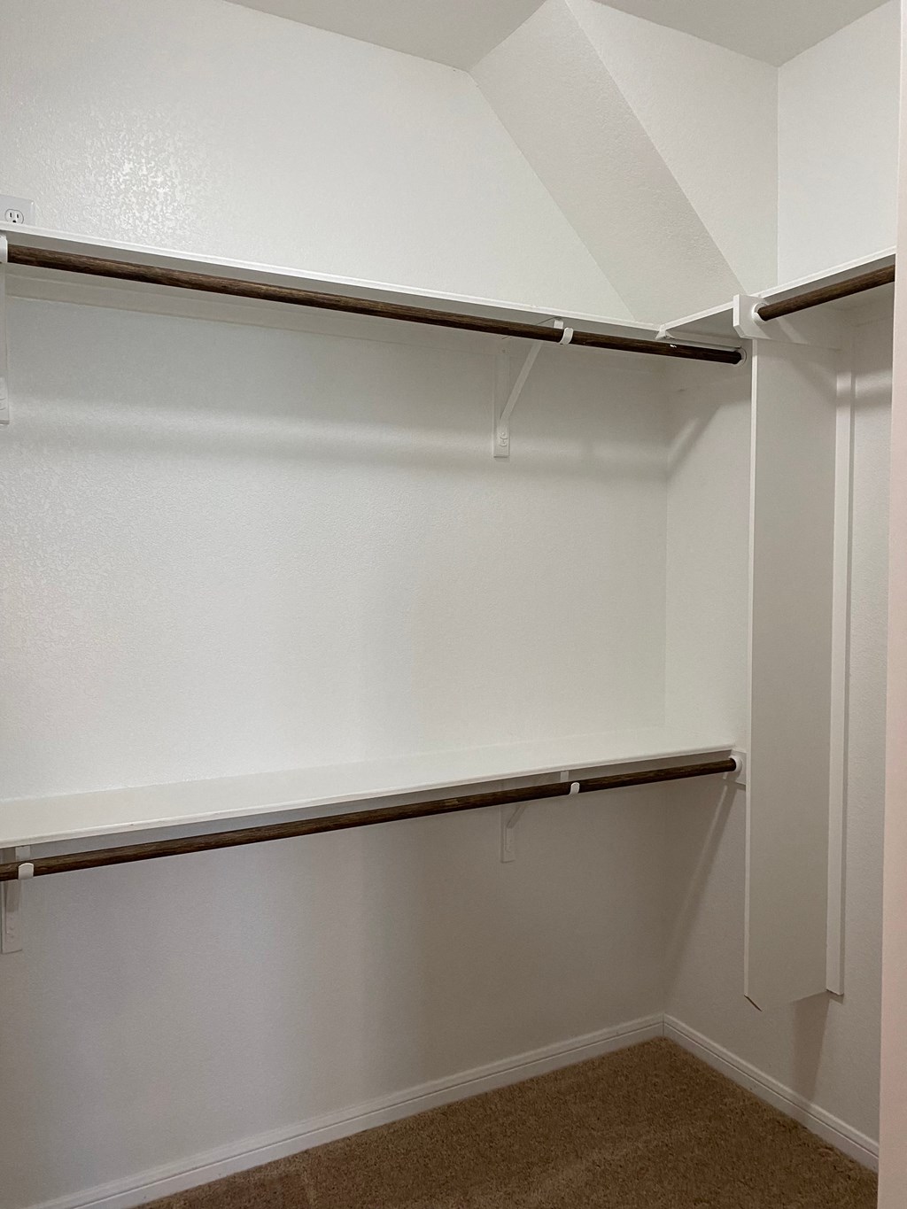 an empty closet in a room with a white wall and aretchedretchedretched shelf