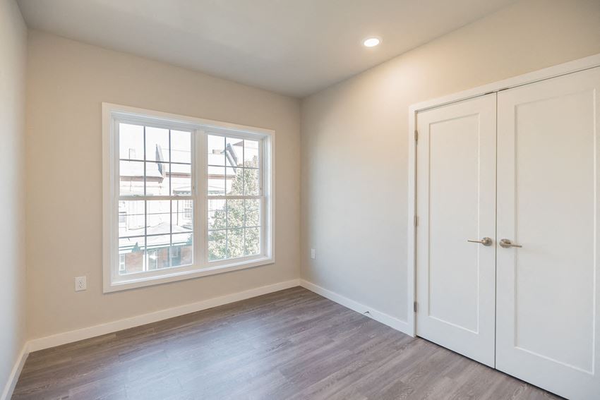 an empty bedroom with white doors and a window