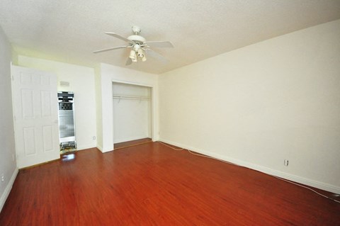 an empty living room with wood floors and a ceiling fan