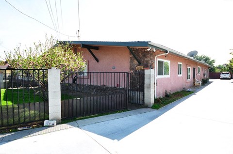 a pink house with a fence and a driveway