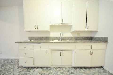 an empty kitchen with white cabinets and a sink