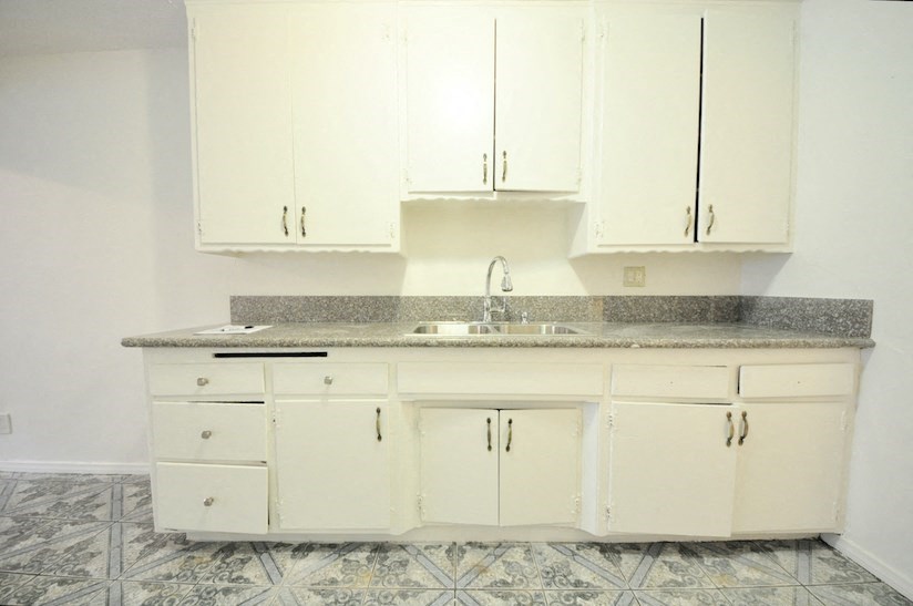 an empty kitchen with white cabinets and a sink