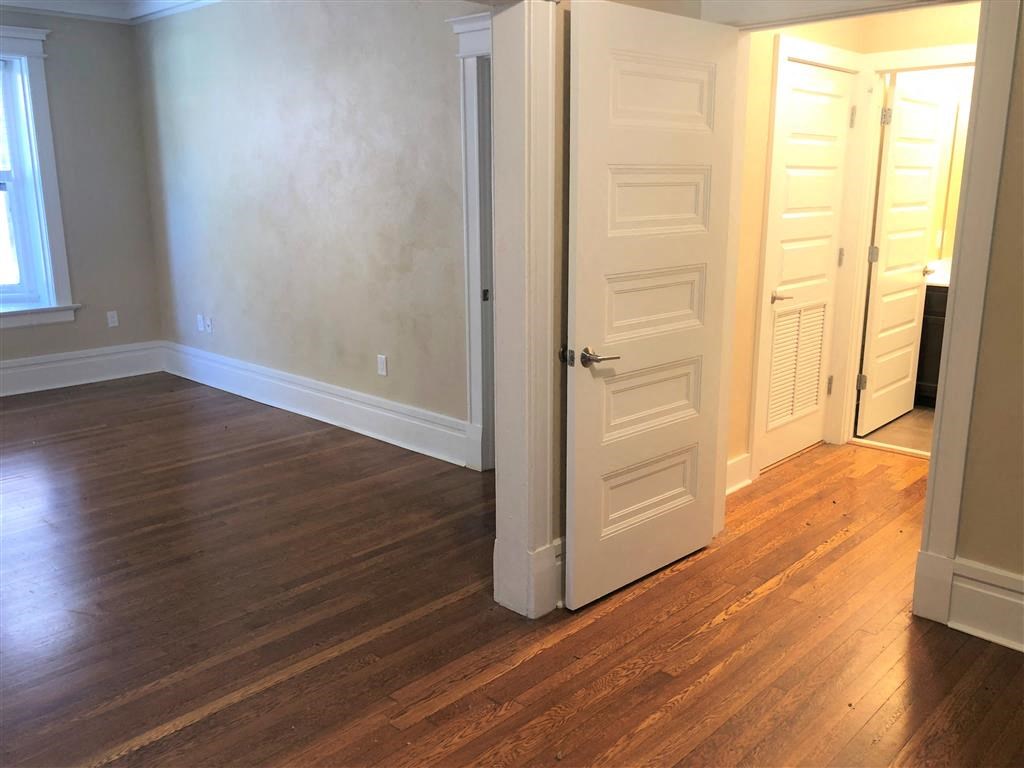 an empty room with an open door and wood floors