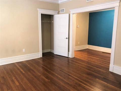 an empty living room with wood floors and a closet