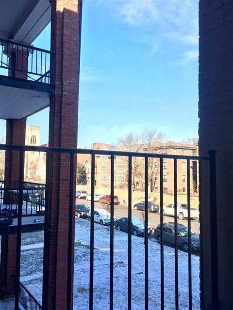 A view from a balcony looking out at a parking lot and buildings.