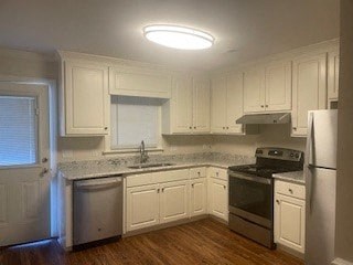 A kitchen with white cabinets and a wooden floor.