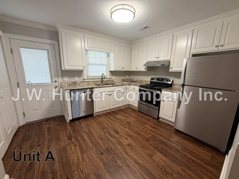 A kitchen with wooden floors and white cabinets.