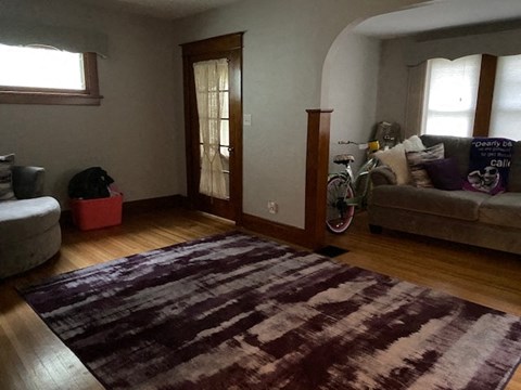 A room with a rug on the floor and a bicycle leaning against the wall.