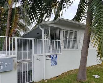the side of a house with a fence and a palm tree