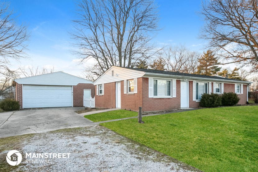 a brick house with a white garage and a driveway